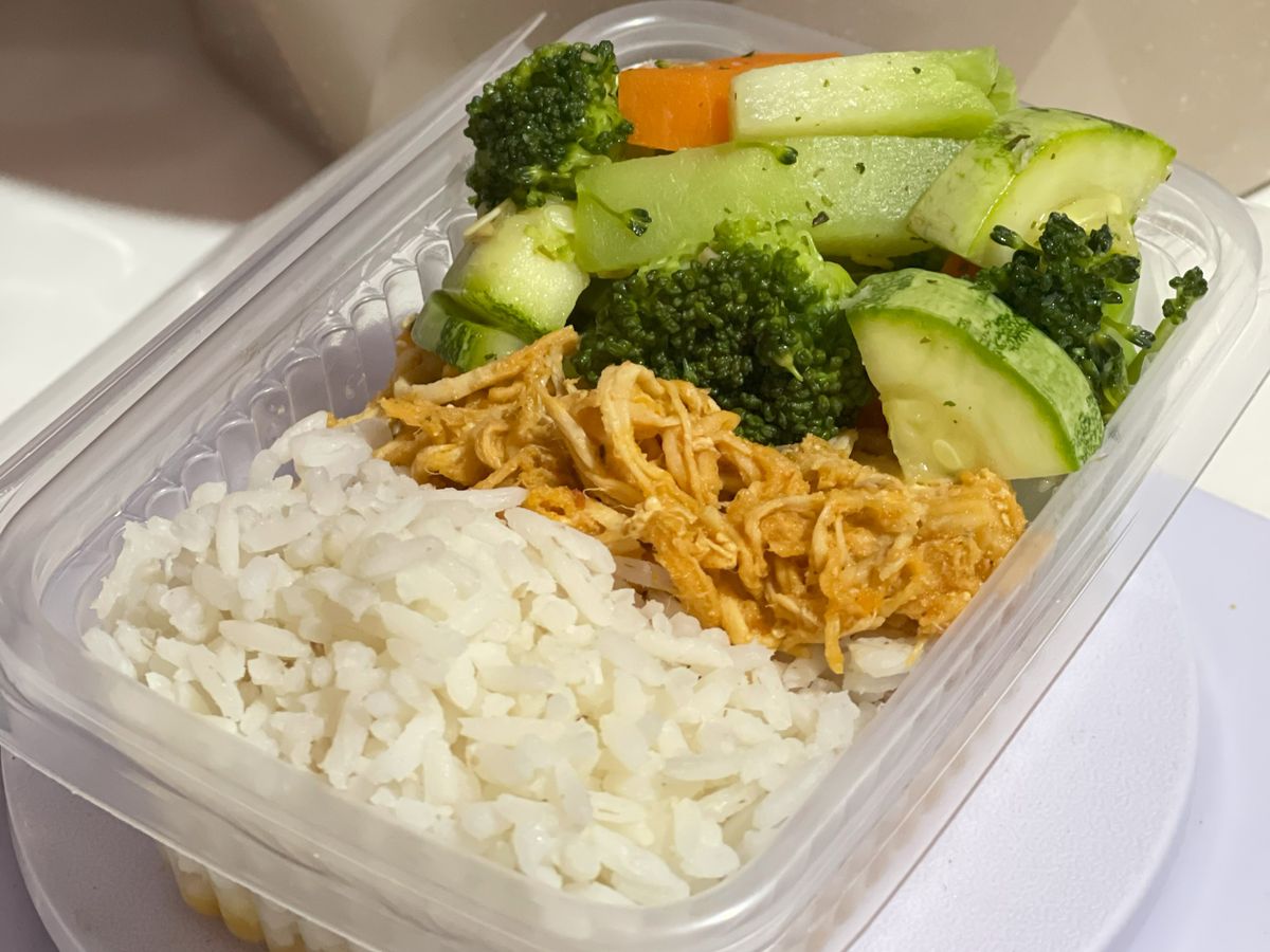 Three glass containers filled with rice, corn, olives, tomatoes, cucumbers, and lentils